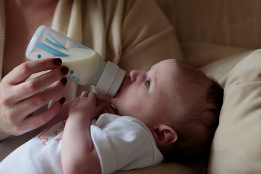 Mother feeding a baby with a bottle of expressed milk using an electric breast pump